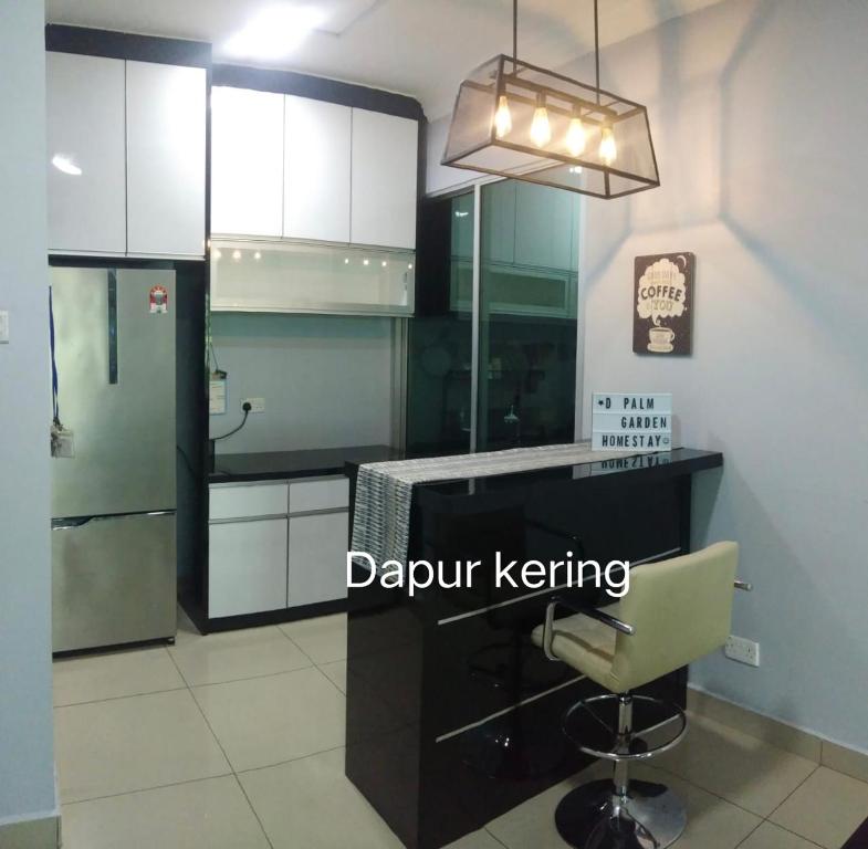 a kitchen with white cabinets and a desk with a chair at D' Palm Garden Homestay Lahad Datu. in Lahad Datu