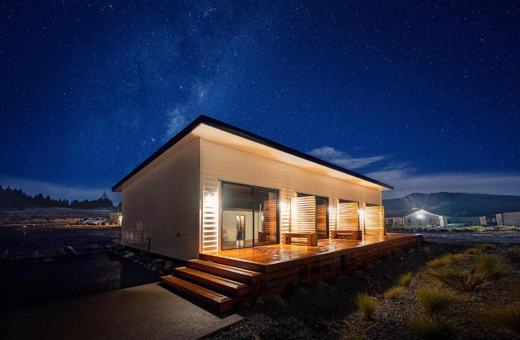 una pequeña casa con terraza por la noche en Alpine Studio Coulson en Lake Tekapo