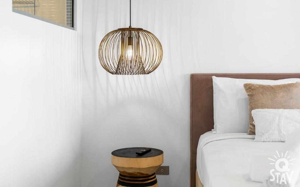 una camera da letto con un letto con un tavolo e una lampada di The Wave - QStay a Gold Coast