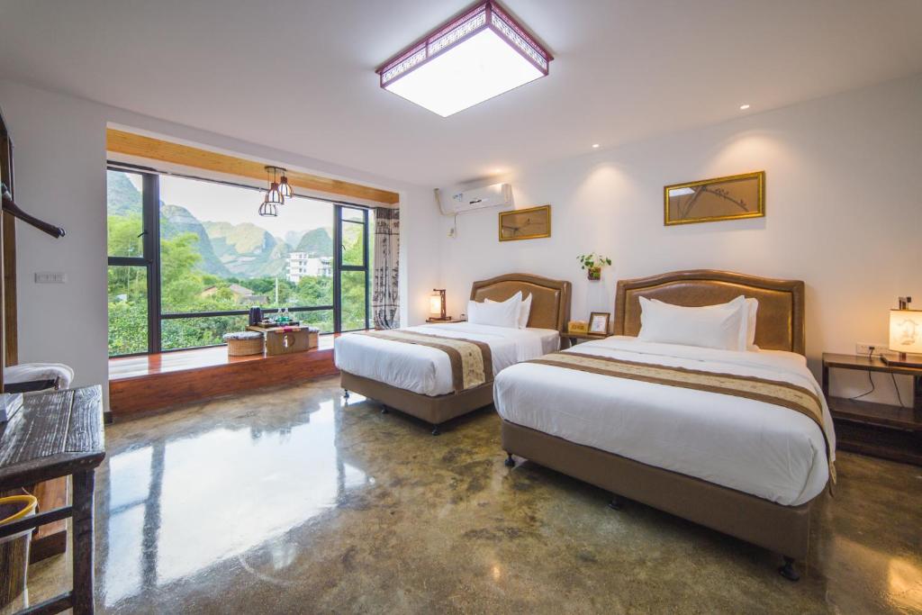een slaapkamer met 2 bedden en een groot raam bij Poetic Leisure Courtyard Hotel in Yangshuo