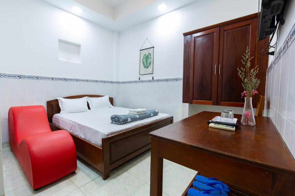 a bedroom with a bed and a desk and a red chair at Hoa Cúc Phương Hotel Dĩ An - Bình Dương in Dĩ An