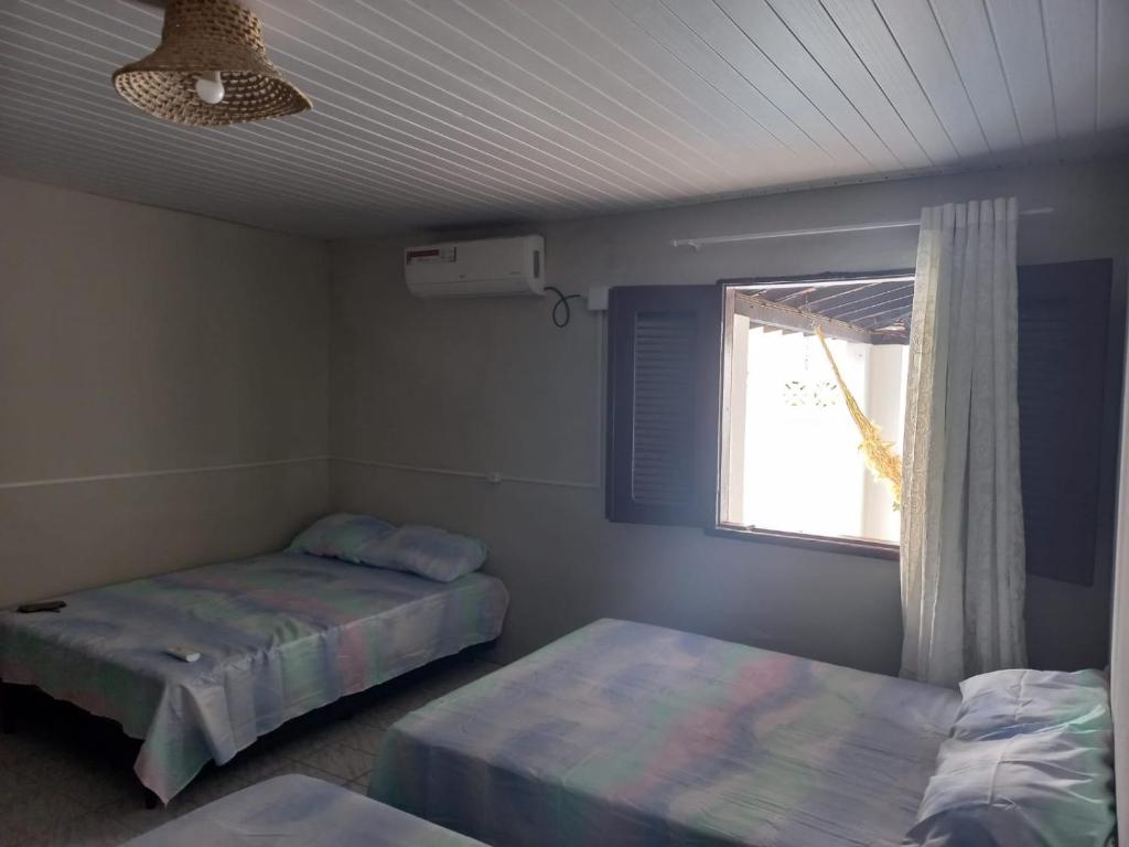 a bedroom with two beds and a window and a ceiling at Pousada Recanto do Mar in Tutóia