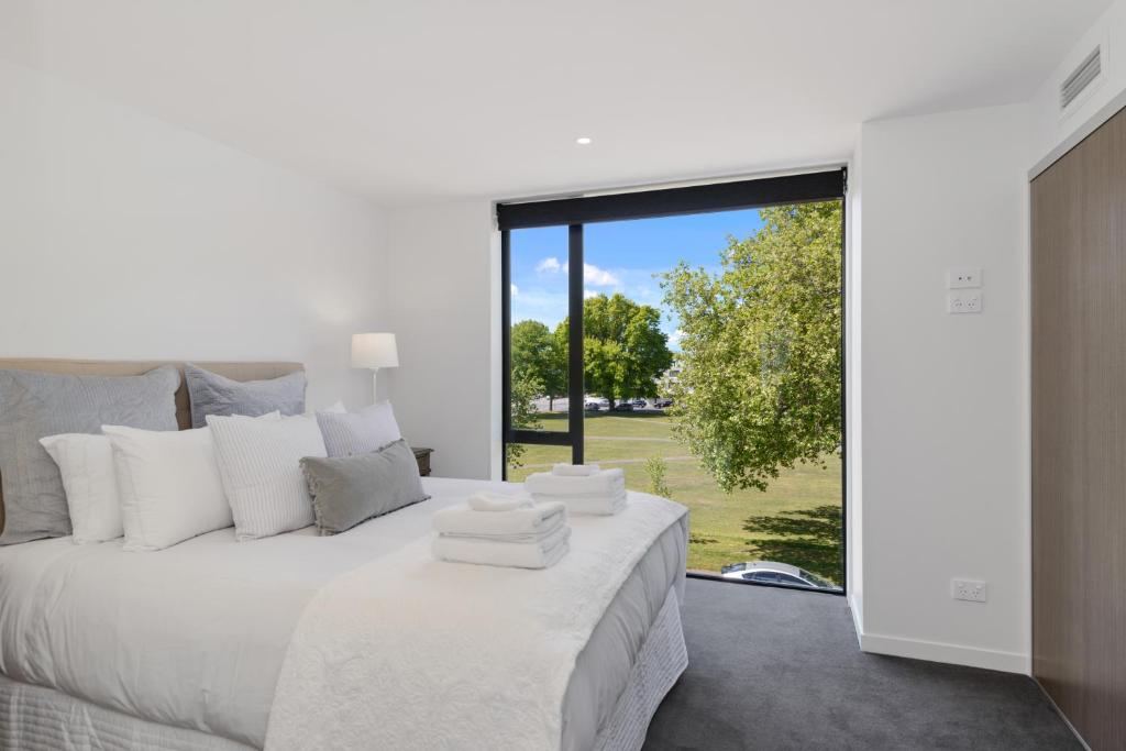 a bedroom with a white bed with a large window at Latimer View Apartment in Christchurch