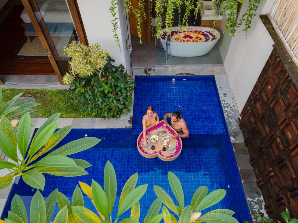 dos chicas jugando en una piscina con tabla de aogie en Teratai Villa Canggu by Ini Vie Hospitality en Canggu