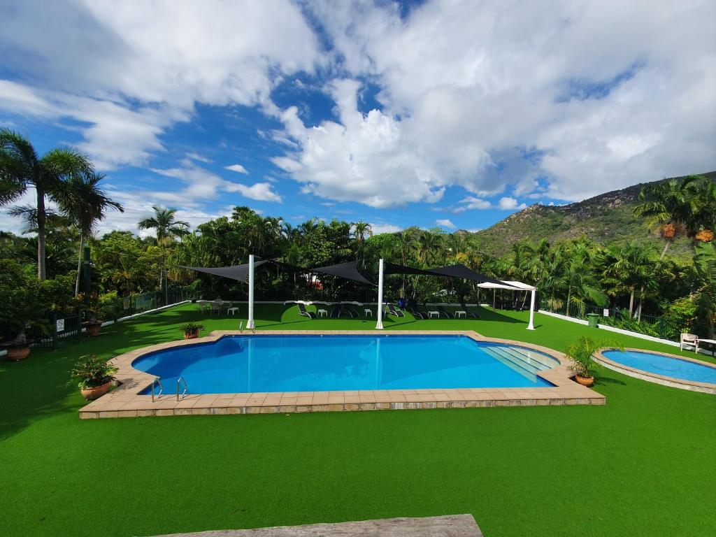 an image of a swimming pool with green grass at Island Serenity on Magnetic Island in Nelly Bay