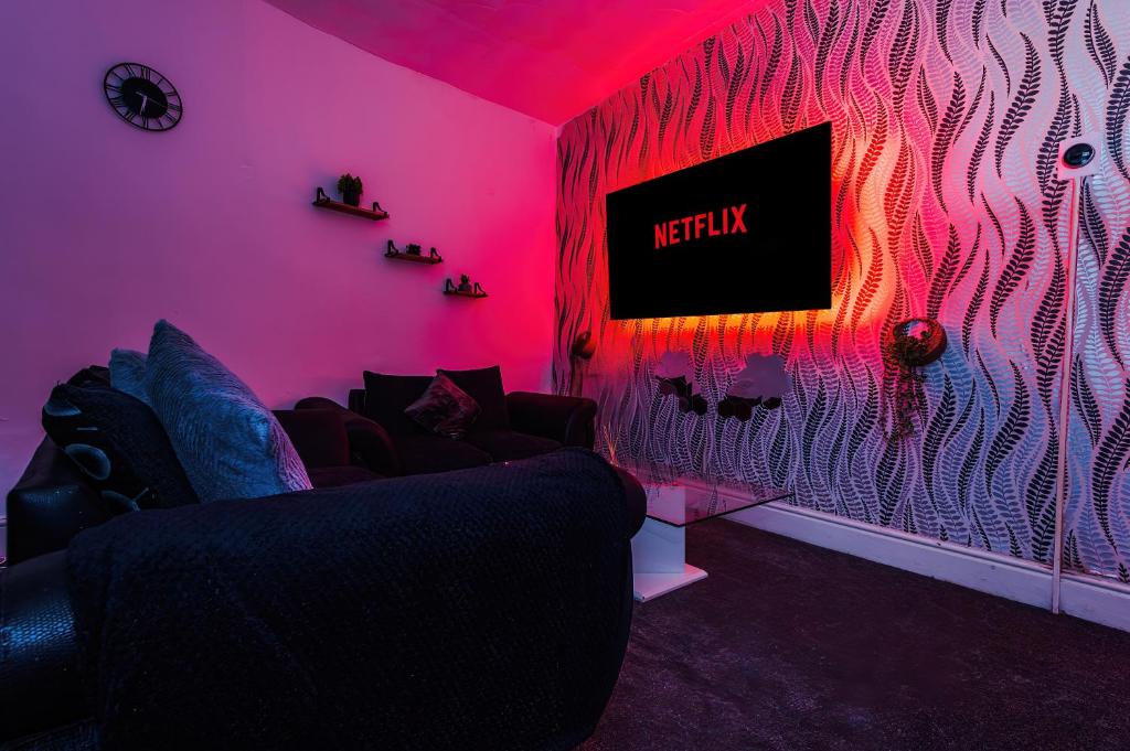 un soggiorno con divano in una camera rosa di 65 Inch TV & Luxurious 2 Bedroom Suite for Your Ultimate Getaway a Bradford