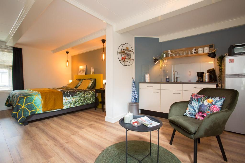een slaapkamer met een bed, een stoel en een tafel bij d' âld skoalle - Sfeervol appartement in oude school. in Wijtgaard