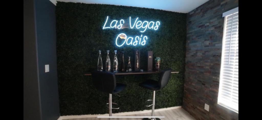 een bar met twee stoelen en een neonbord op een muur bij Las Vegas Oasis in Las Vegas