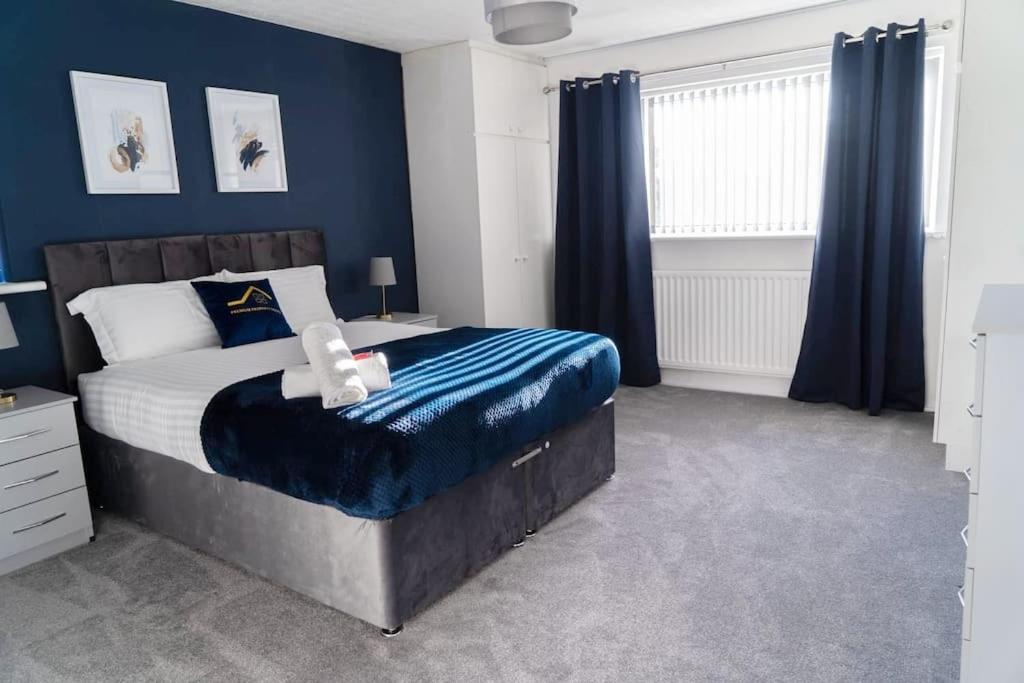 ein Schlafzimmer mit einem großen Bett mit blauen Wänden in der Unterkunft Solihull 5 Bed Home near NEC/Bham airport/JLR/HS2 in Solihull