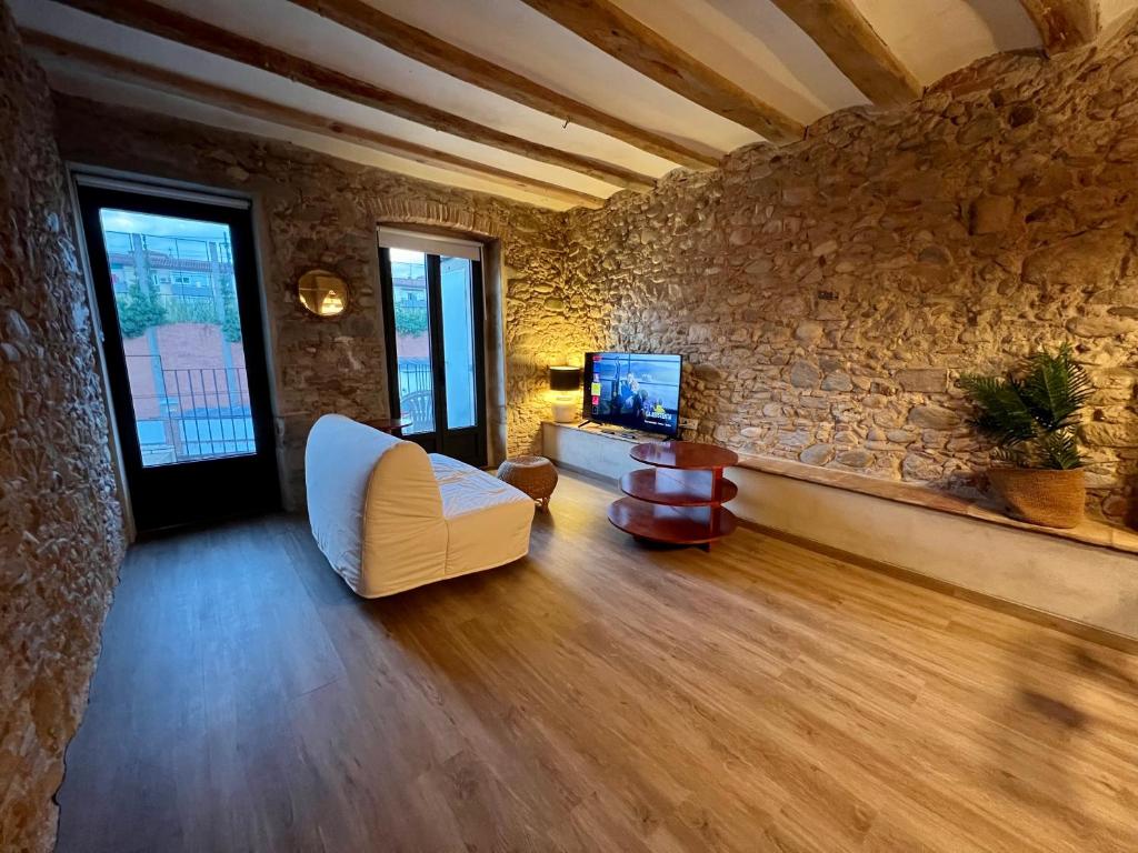 Precioso Girona largas estancias في جيرونا: غرفة معيشة مع أريكة بيضاء وجدار حجري