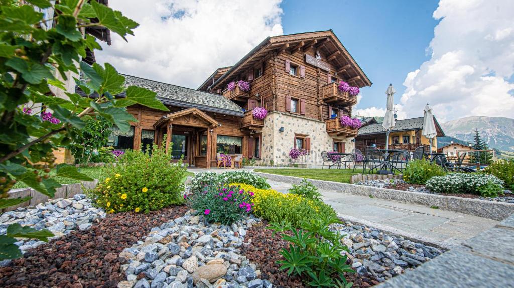 a log home with a garden in front of it at Hotel Capriolo in Livigno