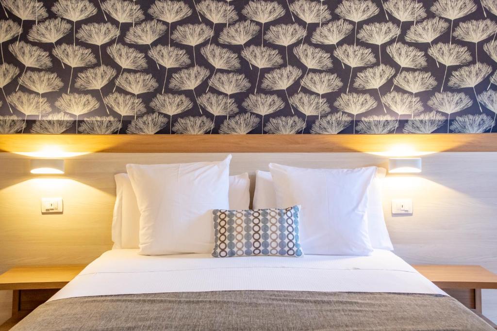1 dormitorio con 1 cama con almohadas blancas y pared en Feudogrande Bio Relais Hotel, en Fiumefreddo di Sicilia