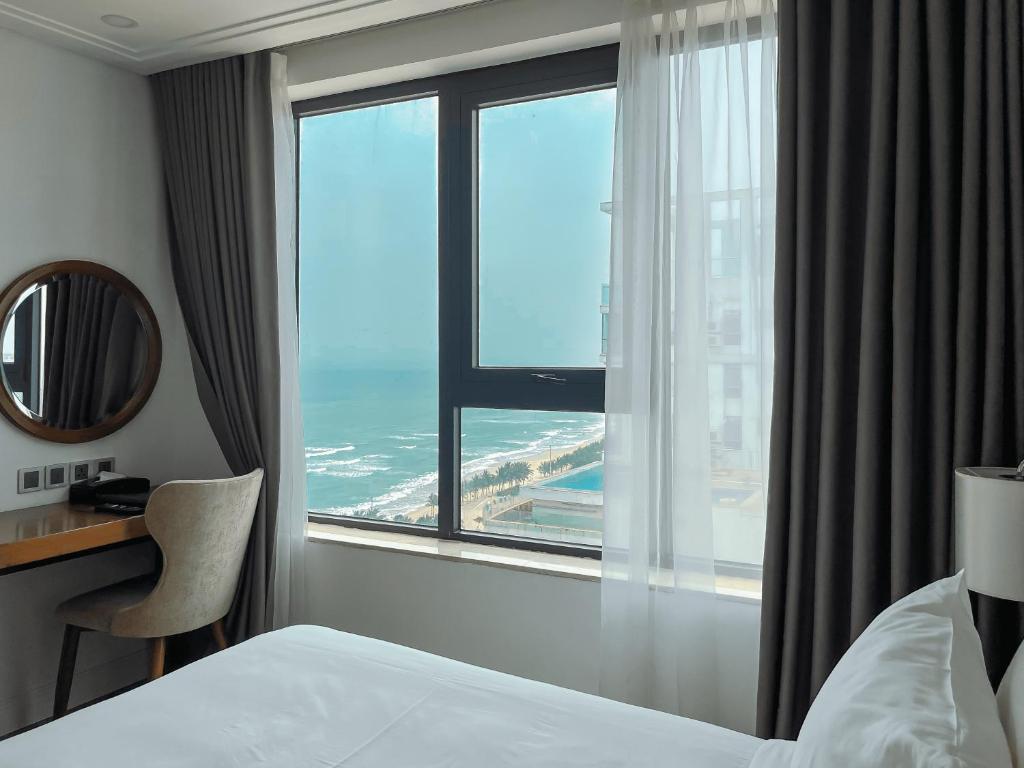 a hotel room with a bed and a desk and a window at Paris Deli Danang Beach Hotel in Danang