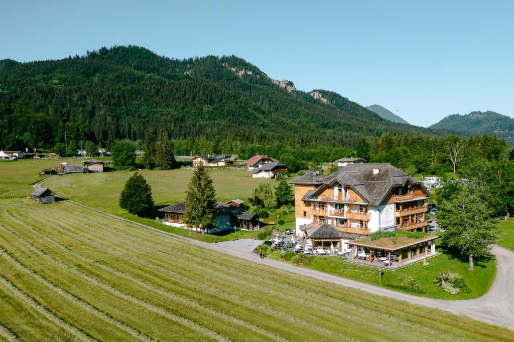 une vue aérienne sur une grande maison dans un champ dans l'établissement Das Leonhard - Naturparkhotel am Weissensee, à Weissensee