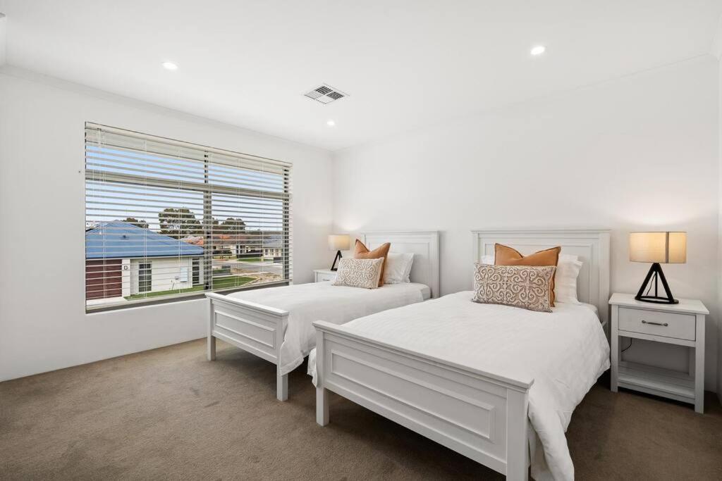 a white bedroom with two beds and a window at Modern Minimalistic Home 3BR in Perth