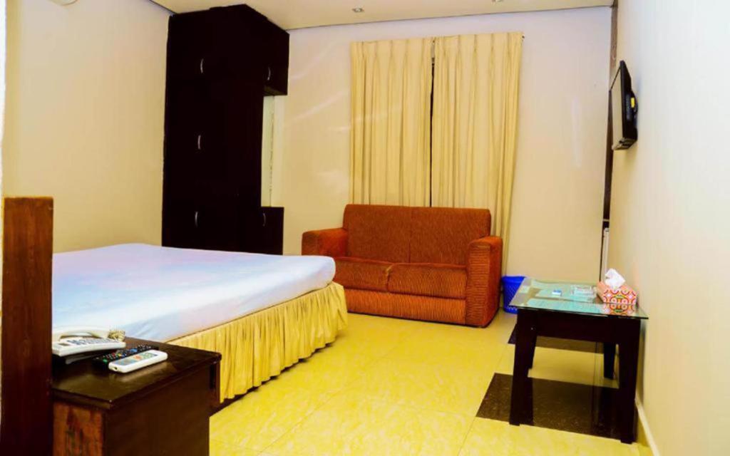 a bedroom with a bed and a chair and a table at Royal Living Hotel & Suites in Chittagong