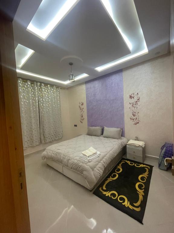 a bedroom with a large bed with a black rug at LH résidence Mezouar 1 in Laayoune