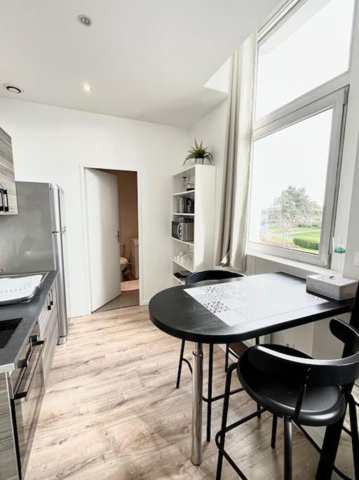 a kitchen with a table and chairs and a window at ROME - Studio meublé à Reims in Reims