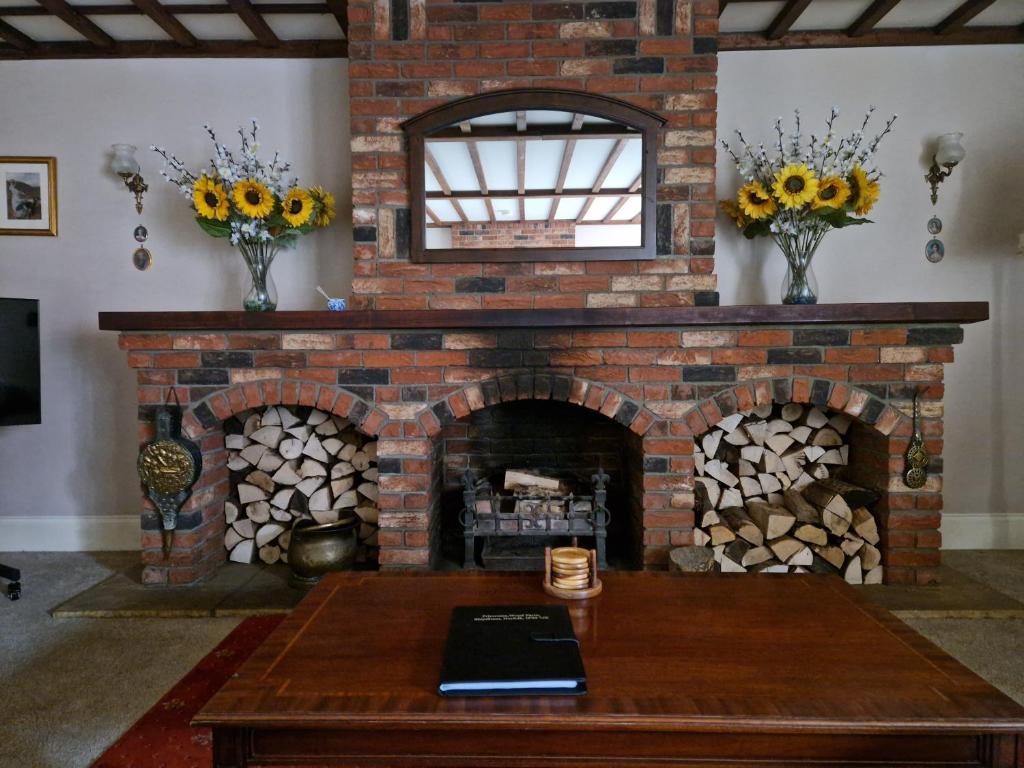 a living room with a brick fireplace with a table at Primroses, Wood Farm in Shipdham