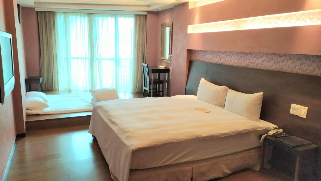 ein Schlafzimmer mit einem großen Bett und einem Fenster in der Unterkunft Bitan Hotel in Xindian