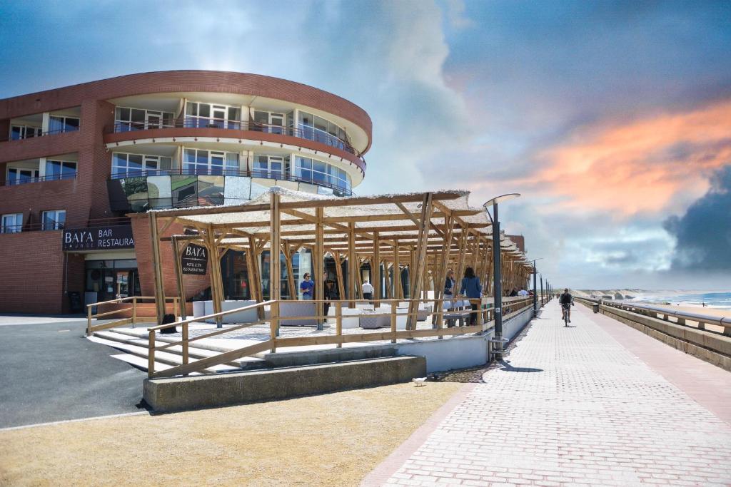 a building on the beach with people walking in front of it at Baya Hotel in Capbreton