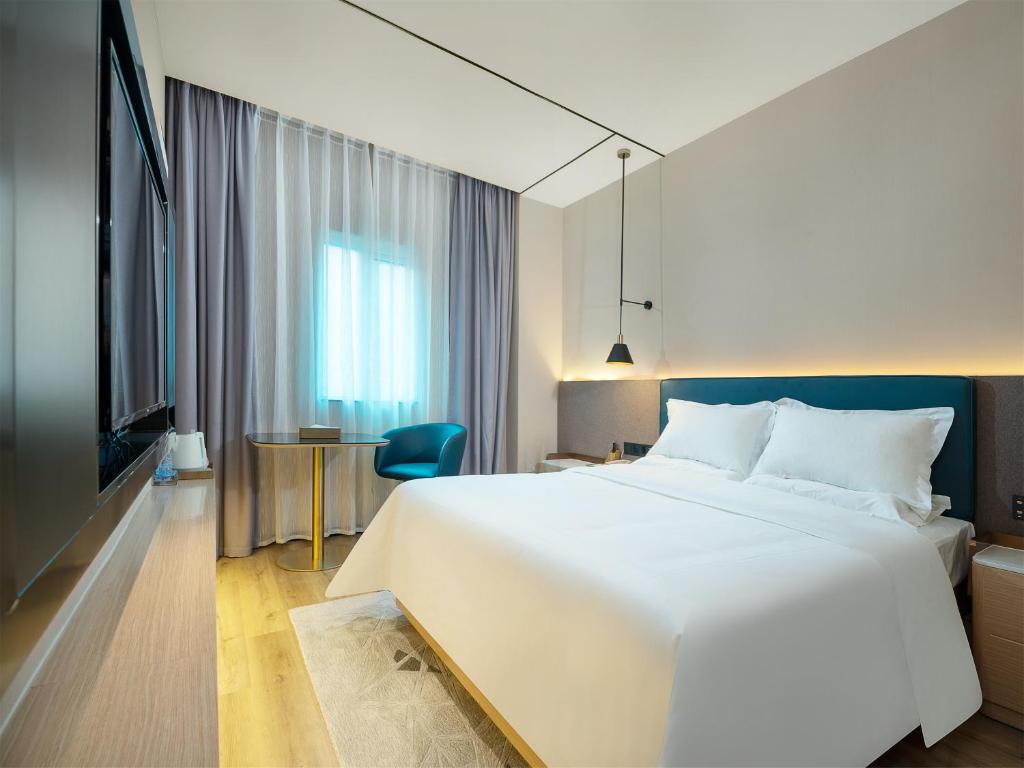 - une chambre avec un grand lit blanc et une table dans l'établissement Chaoman Hotel -Guangzhou Shijing City Plaza Xiaoping Subway Station, à Canton