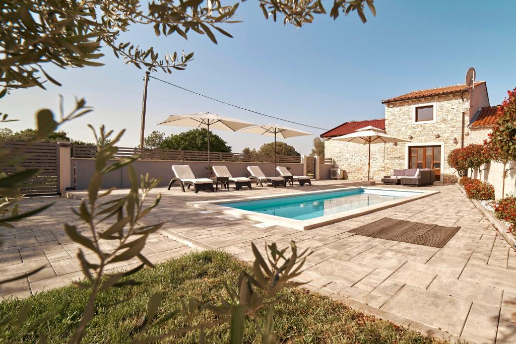 - une piscine avec des chaises et une maison dans l'établissement Haus Mila, à Pavicini