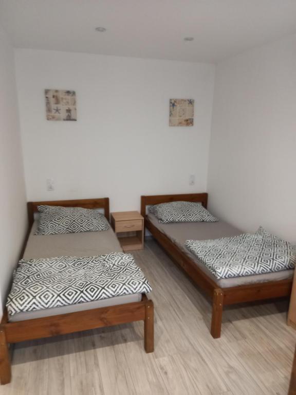 Habitación con 2 camas, paredes blancas y suelo de madera. en Noclegi Stacja Wilkołaz, 