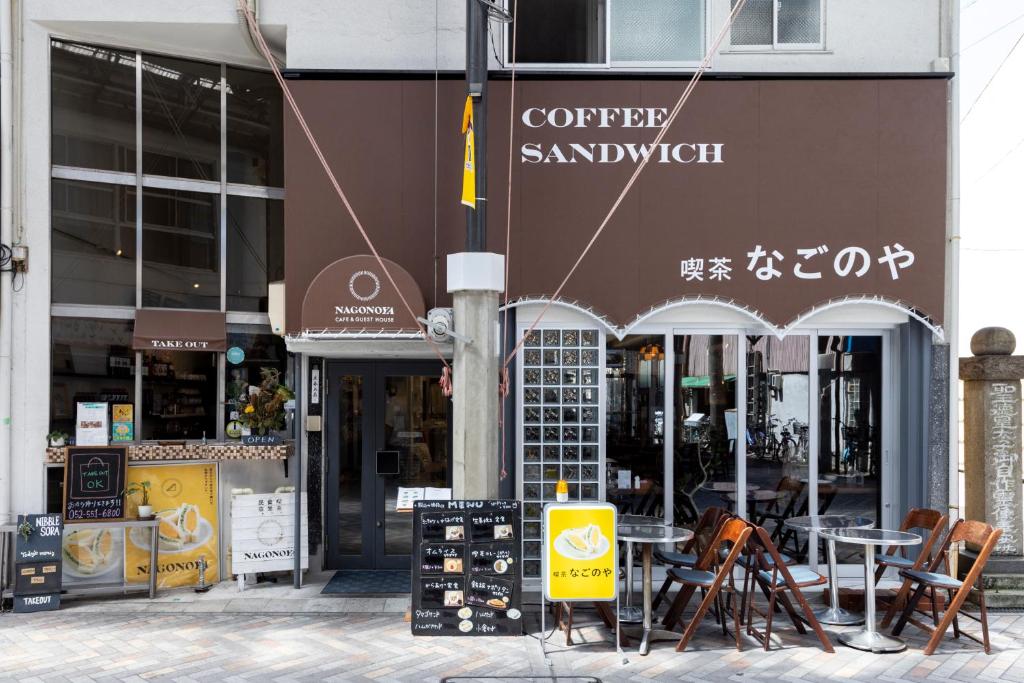 Cafe & Guest House Nagonoya في ناغويا: مقهى فيه طاولات وكراسي امام مبنى