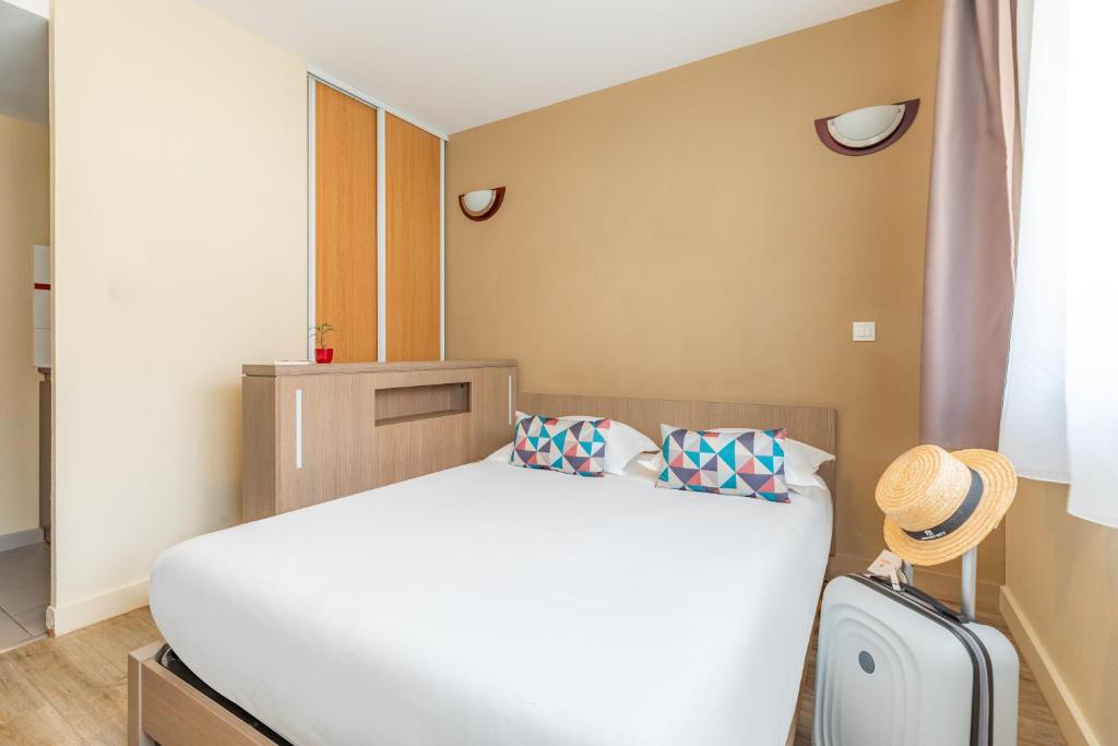 a bedroom with a white bed and a suitcase at Appart'City Classic Nice Acropolis in Nice