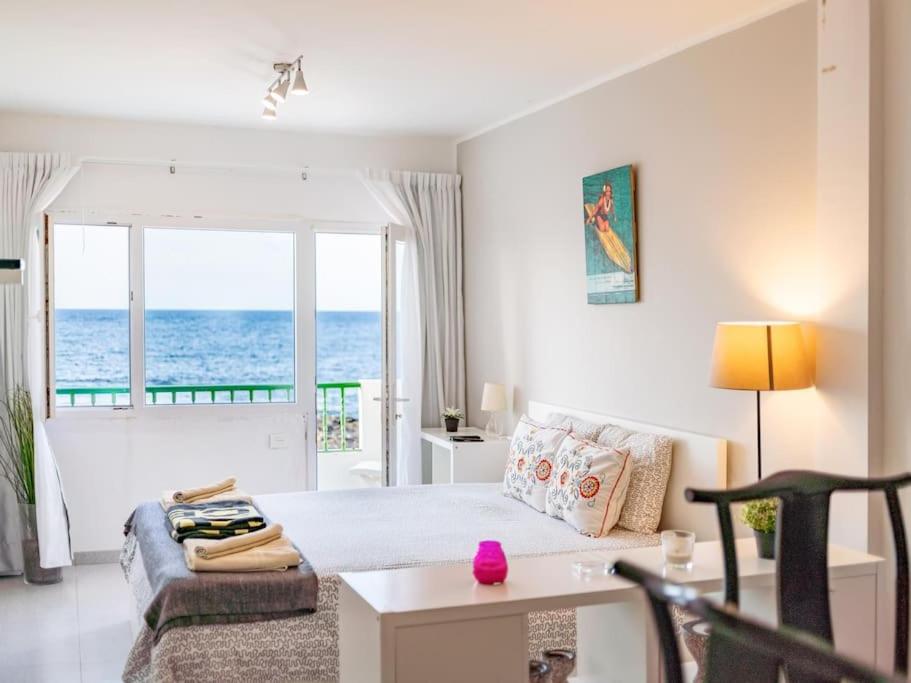 1 dormitorio con cama, mesa y sofá en Weybeach3 ocean frontline,sea view,private terrace, en La Santa