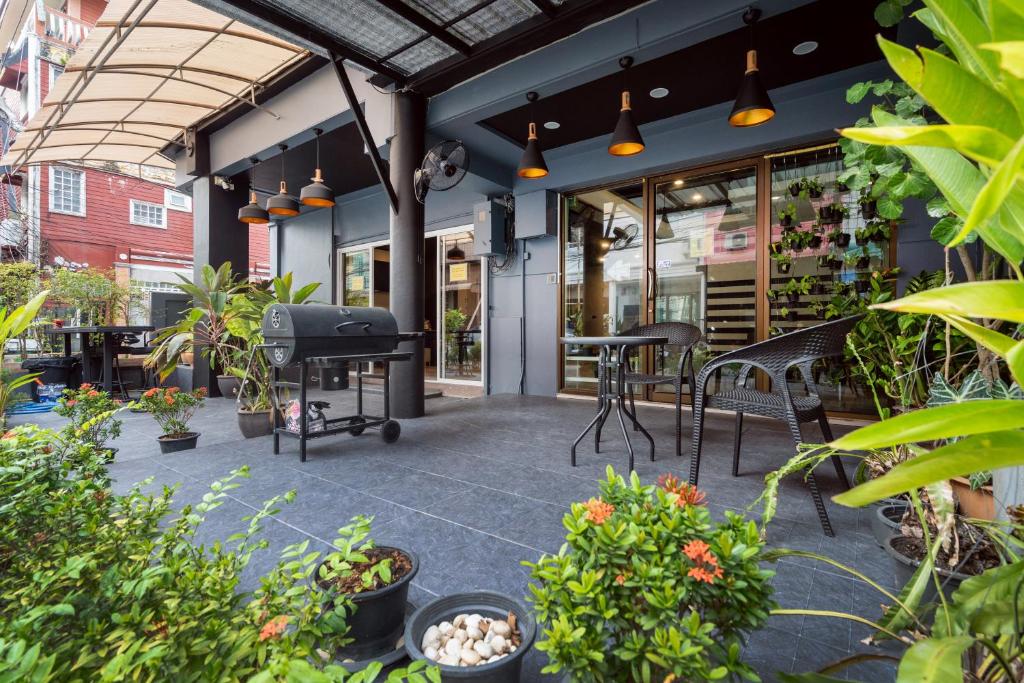 Black Pantera Hostel في شاطيء باتونغ: فناء به طاولات وكراسي ونباتات