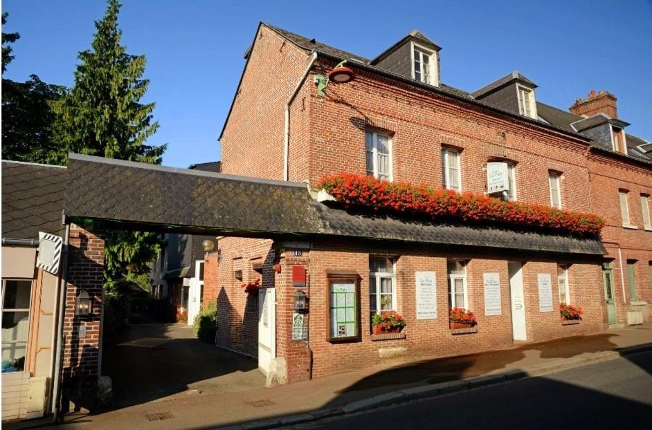 a brick building with flowers on the side of it at Hôtel Restaurant La Paix La Robe et le Palais in Forges-les-Eaux