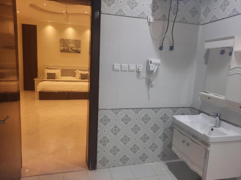 a bathroom with a sink and a bed in a room at شاليهات و فلل عائلية بمسابح خاصة in Khamis Mushayt