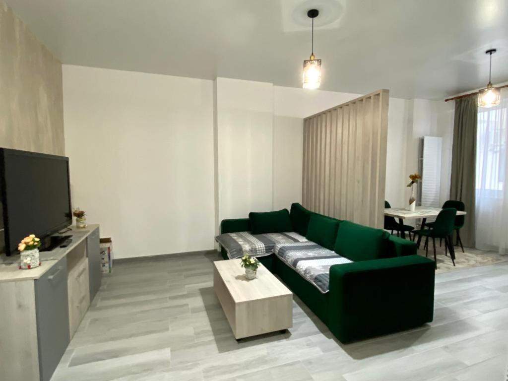ein Wohnzimmer mit einem grünen Sofa und einem Tisch in der Unterkunft Tanya Apartments Nord10 in Mamaia Nord – Năvodari