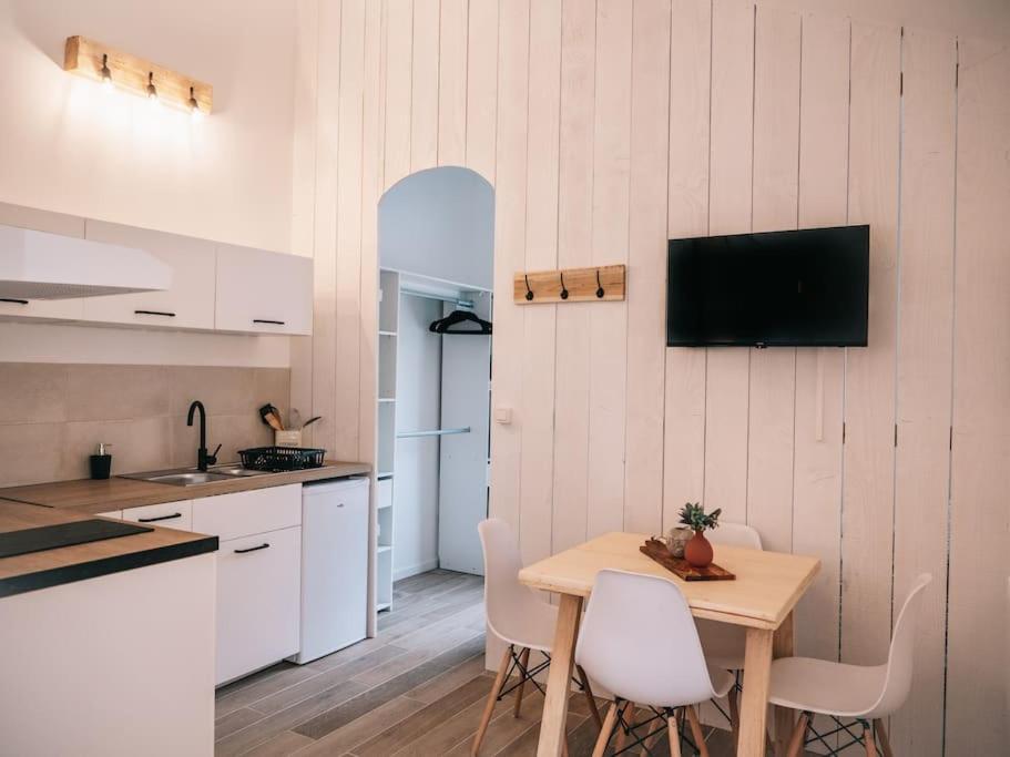 cocina con mesa y sillas y TV en la pared en Le studio du Coutach, en Quissac