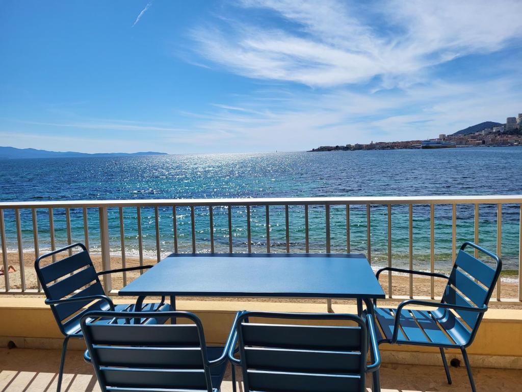 Una mesa y sillas en un balcón con vista al mar. en Sudio bord de mer Ajaccio, en Ajaccio