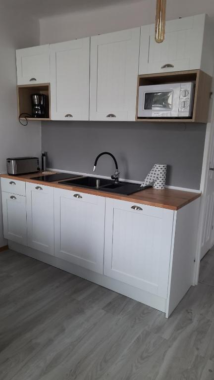 a kitchen with white cabinets and a sink and a microwave at Apartament 3 pokoje z balkonem Asklepios in Świnoujście