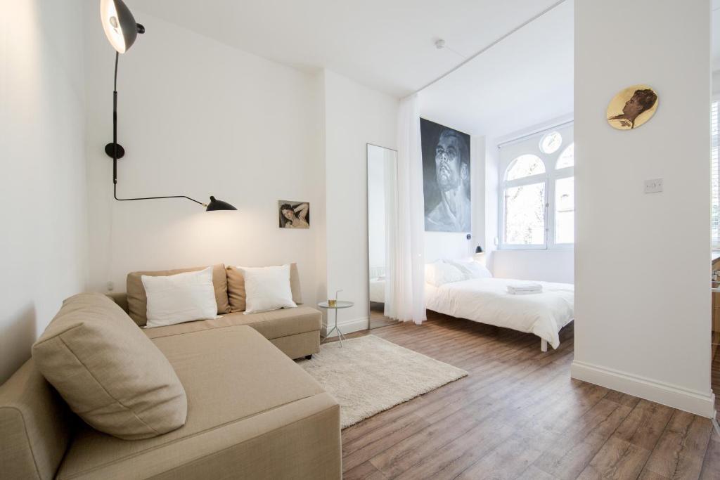 a white living room with a couch and a bed at St. Lukes View, Shoreditch, by the Design Traveller in London