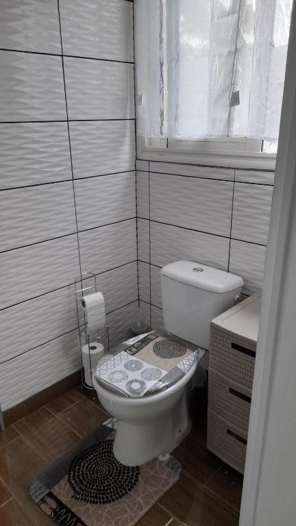 a white bathroom with a toilet and a window at Zen Alliance in Fleurimont