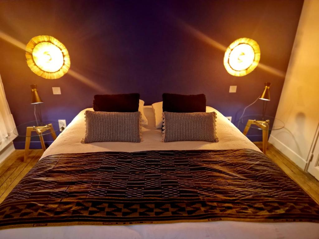 a bedroom with a large bed with two lights on the wall at LES BC BG in Charleville-Mézières