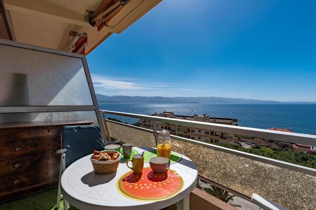 une table avec une assiette de nourriture sur un balcon dans l'établissement Chapelle des Grecs - 1km de la plage, à Ajaccio
