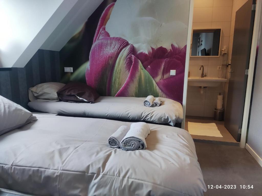 two beds in a room with a painting on the wall at House of Tulips in Hillegom