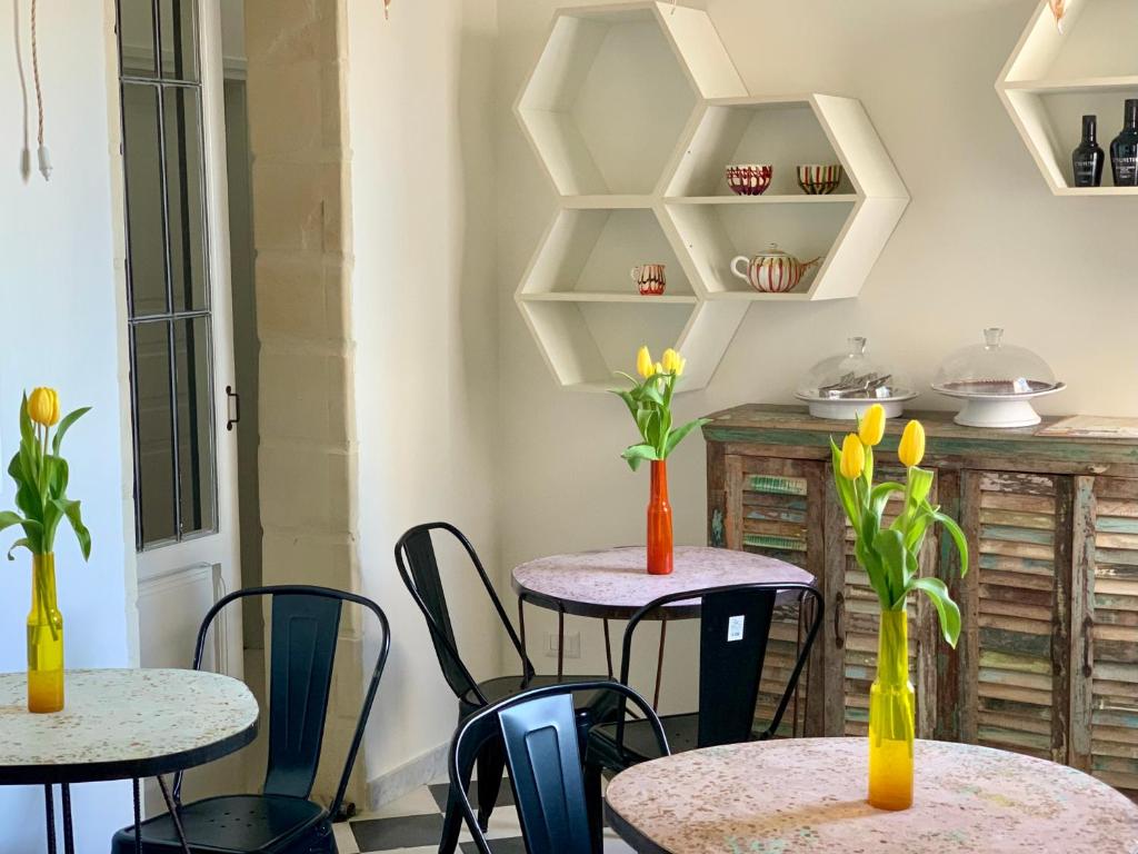 dos mesas con jarrones con flores amarillas. en HABITARE Lecce & Salento, en Lecce