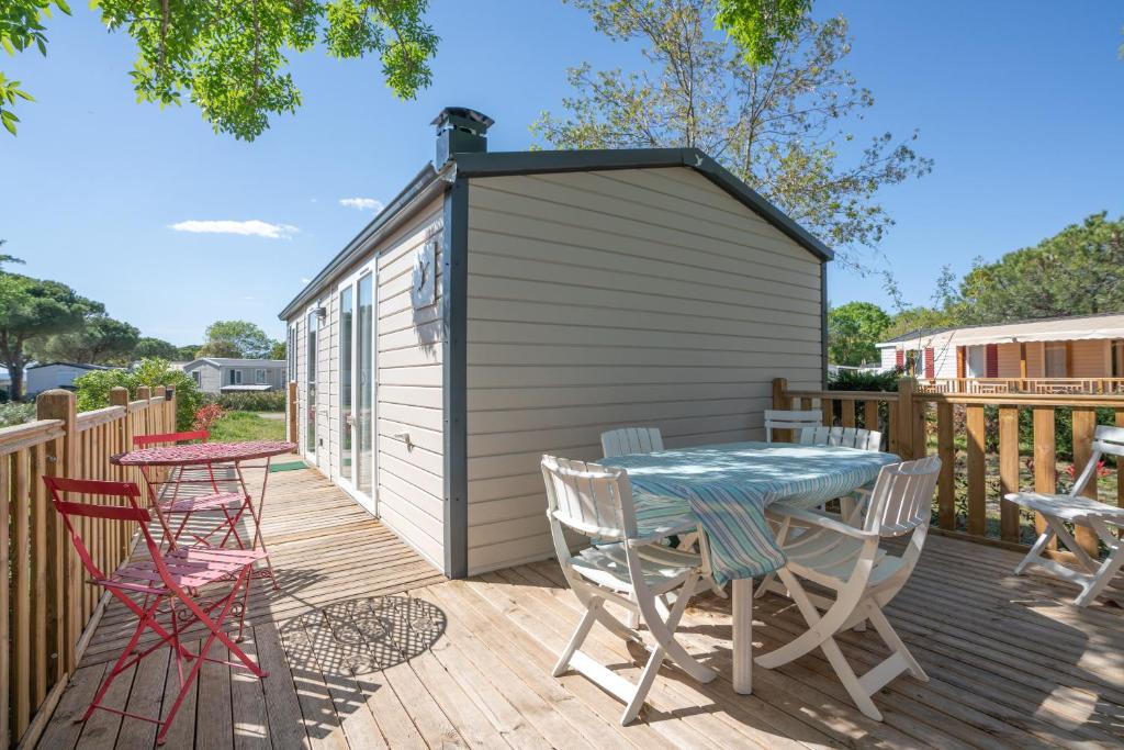 a deck with a table and chairs and a shed at Mobile-home 132 in Lattes