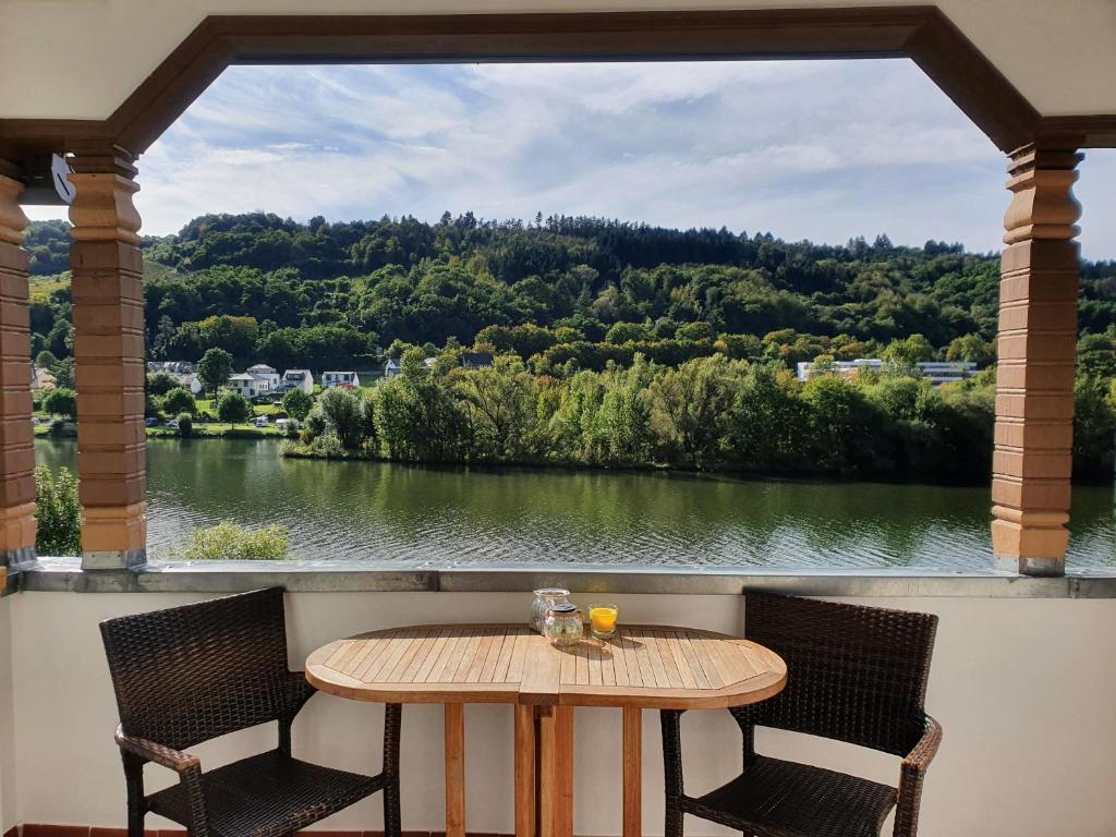 ツェル・アン・デル・モーゼルにあるLuxus Ferienhaus Inselblickのテーブルと椅子、川の景色を望むバルコニー