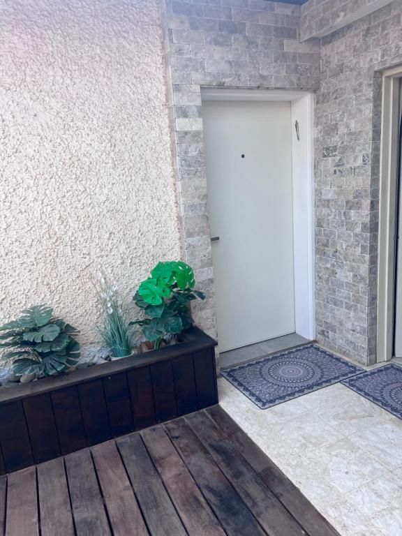 białe drzwi w ceglanej ścianie z roślinami w obiekcie Rina House w mieście Karmiel