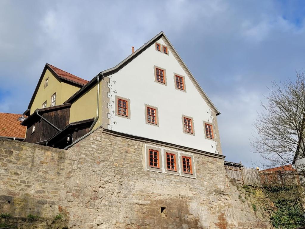una gran casa blanca en la parte superior de una pared de piedra en Die alte Kantorei - historische Ferienwohnung, en Kahla
