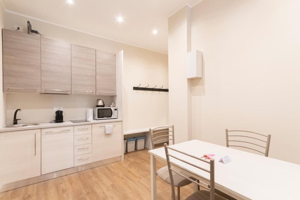 米兰Missori Apartment 1的配有白色橱柜、桌子和椅子的厨房