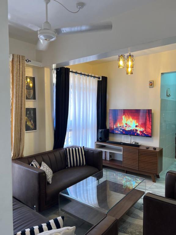 uma sala de estar com um sofá e uma televisão de ecrã plano em Fully furnished one bedroom apartment in Mombasa VOK off nyali road em Mombasa